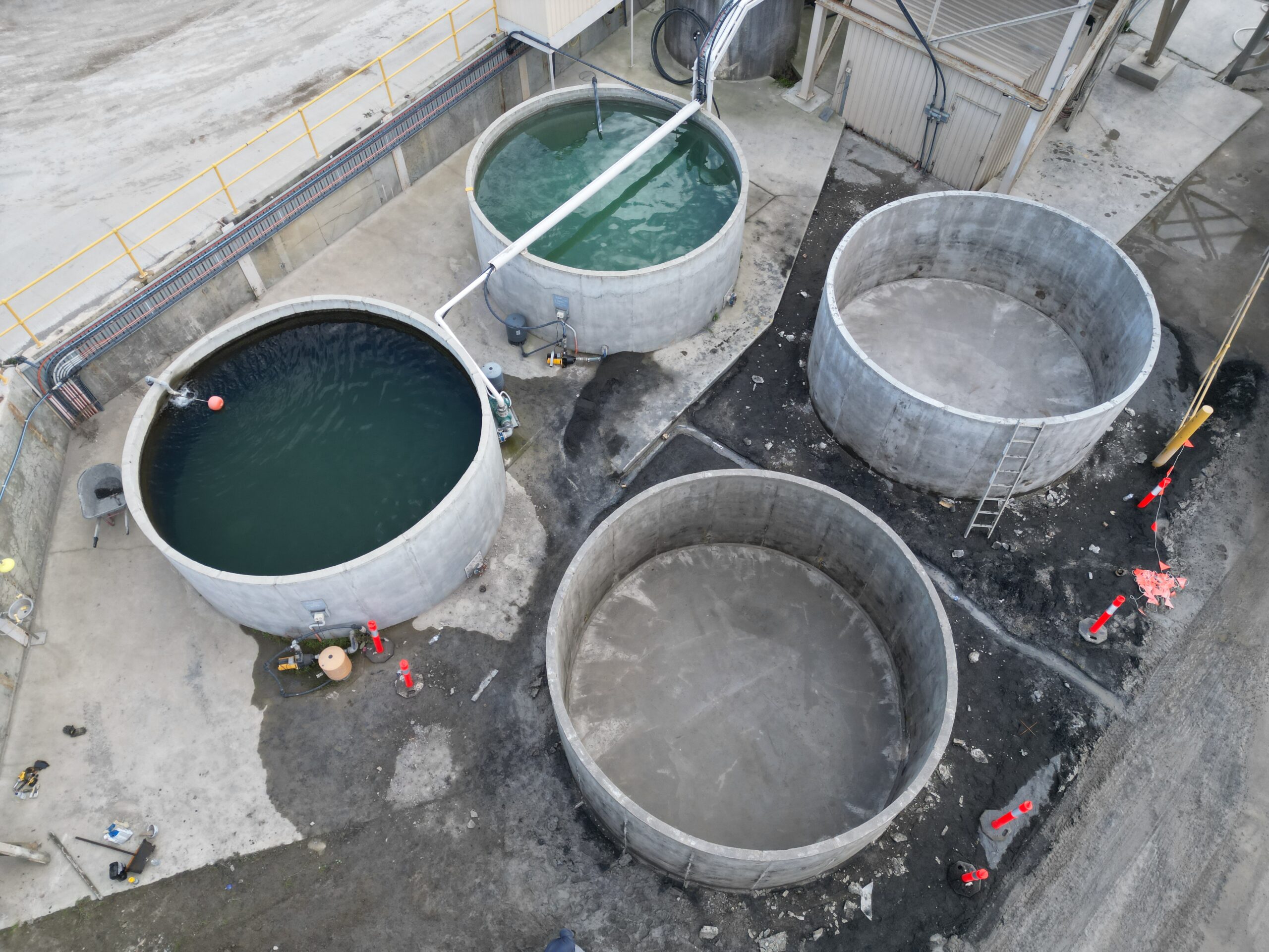 Aerial view of large circular industrial water tanks under construction for storage projects in Victoria